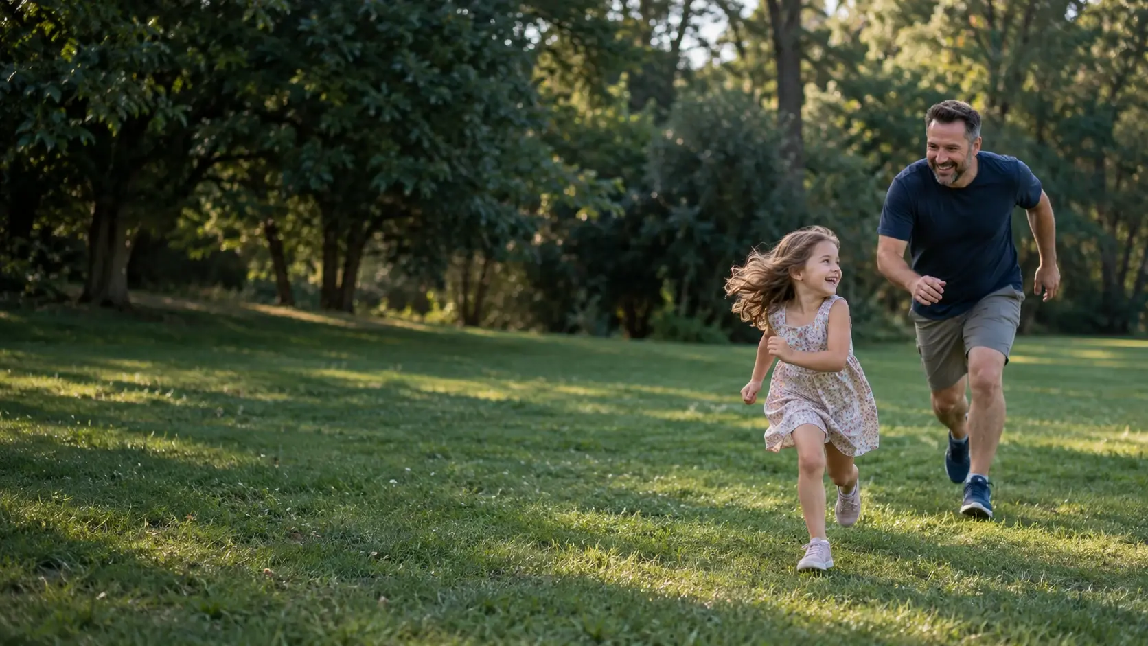 A father playfully chasing his daughter in a game of tag in a park
